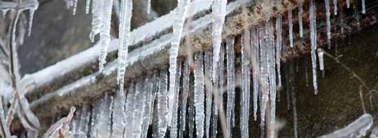Icicles hang from a dark, rough surface.