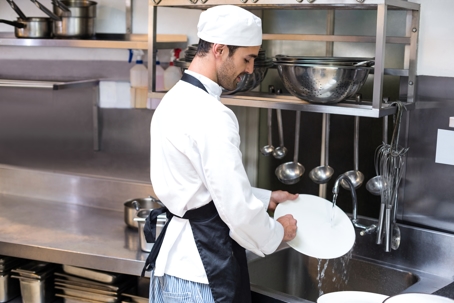 man washing dishes in restaurant